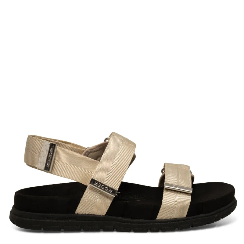 En enkel, moderne sandal i lys elfenbensfarve med to brede remme — én over forfoden og én om anklen — monteret på en kontrastfuld, mørk sål.