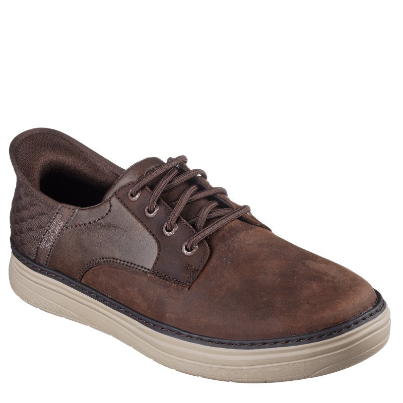 Skechers slip‑ins herre sneakers i en elegant brun med lys kontrastsål. Modellen har elastiske snørebånd og er beklædt med en lækker læderoverdel. Resultatet er en stilren, komfortabel sko – nem at tage på og flot at bære.